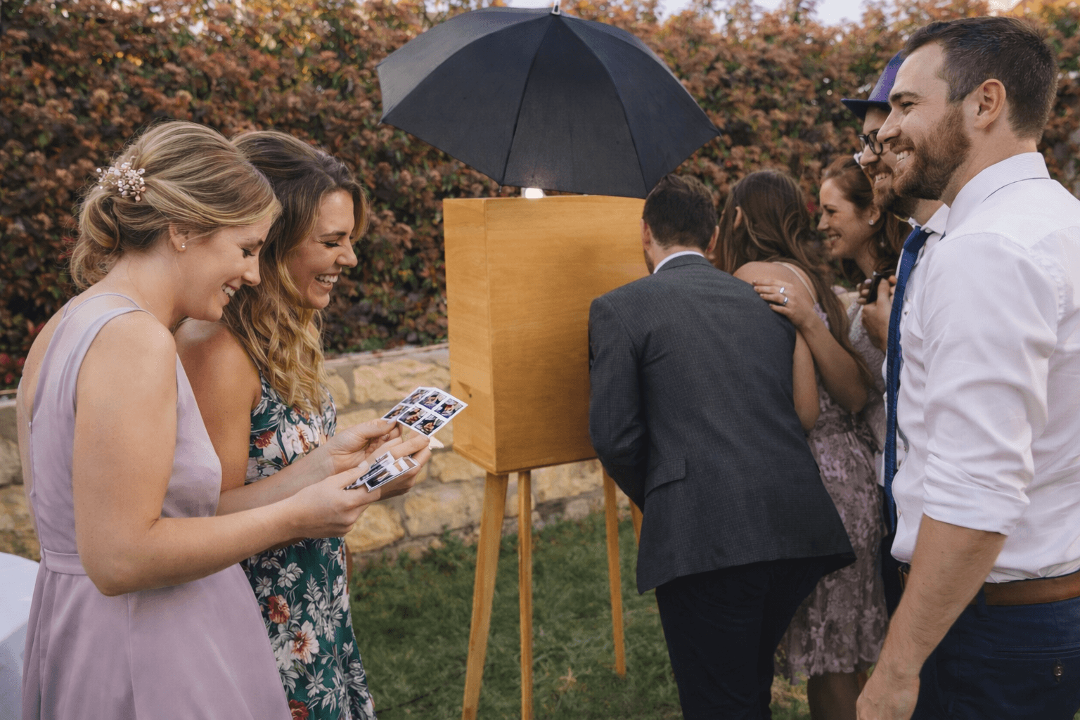 Invitados usando el fotomatón en una boda viendo sus fotos impresas